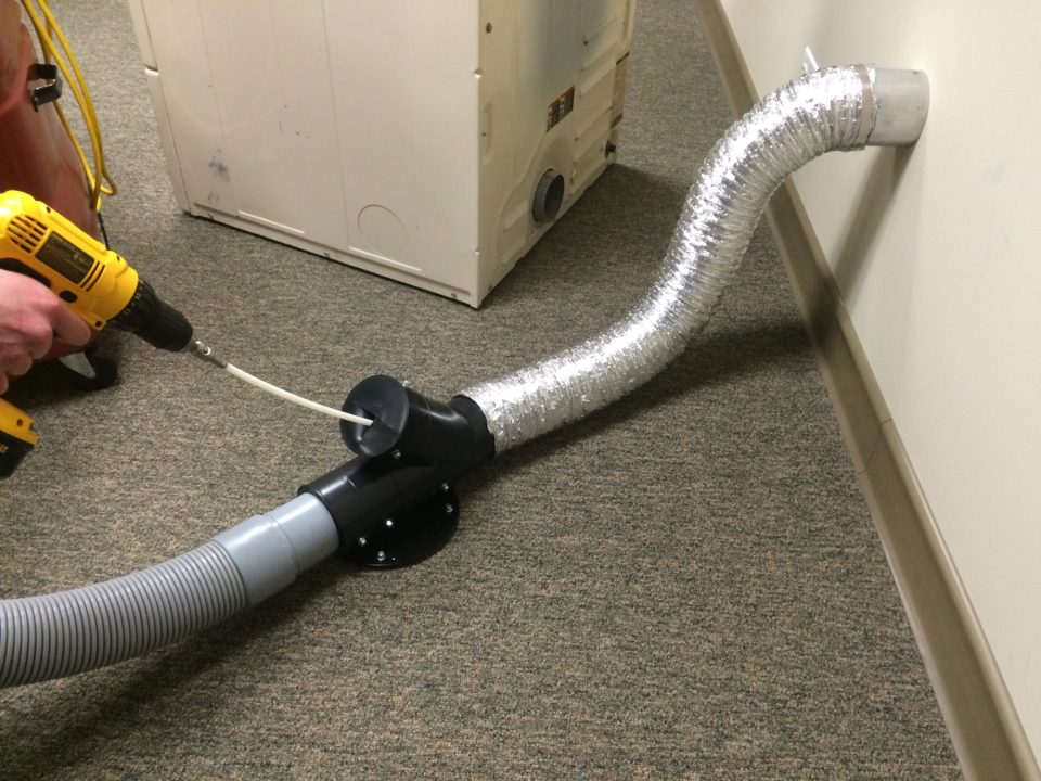 A dryer vent being cleaned using professional tools